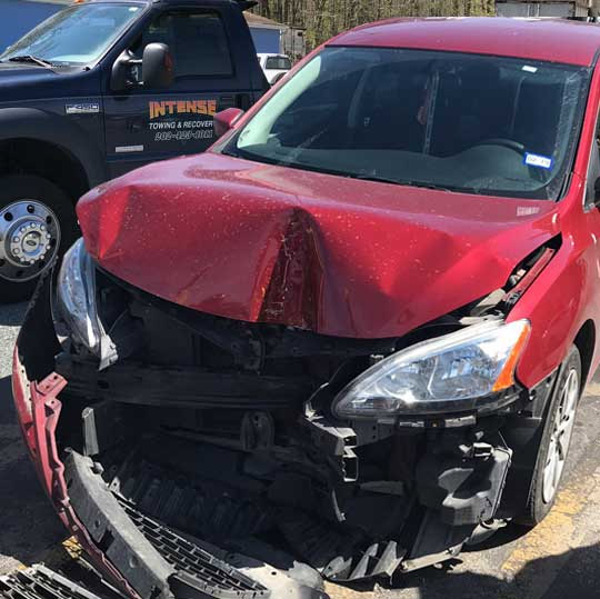 Accident scene in Clinton Maryland with red car and intense towing to truck in background assisting.